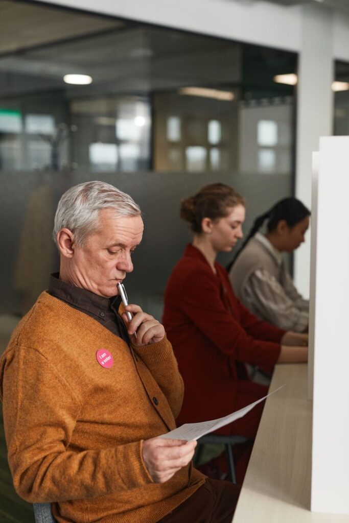 Senior man reviewing a ballot at an indoor polling station on voting day.
